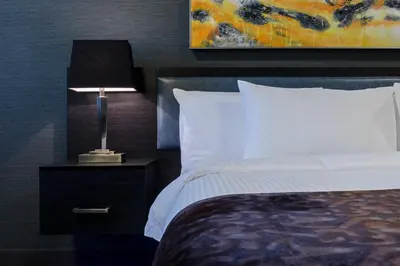 a bedroom with a bed and a lamp on a night stand at Applause Hotel Calgary Airport by CLIQUE in Calgary