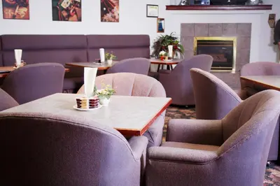 a restaurant with tables and chairs and a fireplace at Country Club Inn in Lacombe