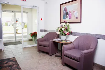 a waiting room with two chairs and a table with flowers at Country Club Inn in Lacombe