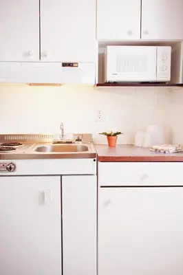 a kitchen with white cabinets and a sink at Country Club Inn in Lacombe