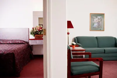 a room with a bed and a couch and a chair at Country Club Inn in Lacombe