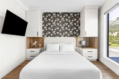 a bedroom with a white bed and a large window at 4BR Luxury Mountain Retreat Private HotTub Sleeps 17 in Canmore