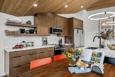 a kitchen with wooden cabinets and a table with flowers at 4BR Luxury Mountain Retreat Private HotTub Sleeps 17 in Canmore