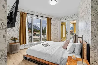 a bedroom with a bed and a large window at 4BR Luxury Mountain Retreat Private HotTub Sleeps 17 in Canmore