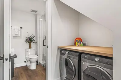 a bathroom with a washing machine and a toilet at Luxury 4BR with Hot Tub Mtn Views 10Min Walk to DT in Canmore