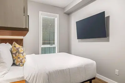 a bedroom with a bed and a tv on the wall at Luxury 4BR with Hot Tub Mtn Views 10Min Walk to DT in Canmore