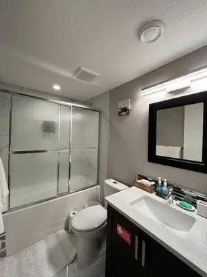 a bathroom with a toilet and a sink and a mirror at Cozy 2BR Retreat | Edmonton SW | Smart TV + Wi-Fi in Edmonton
