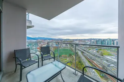 a balcony with two chairs and a view of a city at Sub-Penthouse Condo with Jacuzzi Pool Sauna & Gym in Vancouver