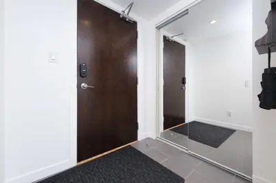 a hallway with a wooden door and a mirror at Sub-Penthouse Condo with Jacuzzi Pool Sauna & Gym in Vancouver