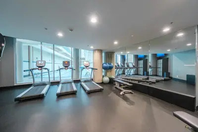 a gym with a row of treadmills and machines at Sub-Penthouse Condo with Jacuzzi Pool Sauna & Gym in Vancouver