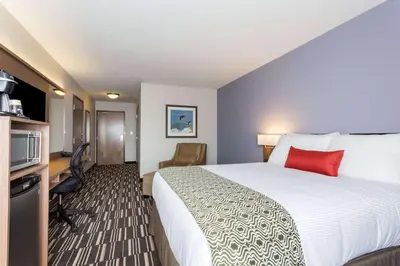 a hotel room with a large bed with a red pillow at Microtel Inn and Suites by Wyndham Kitimat in Kitimat