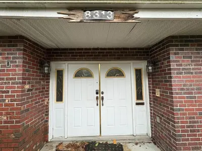a brick house with white doors and a sign above it at North Delta Guest House - Scott Rd & Rapid Transit - Airport 20 Min - Free Parking & Fast Wi-Fi in Delta