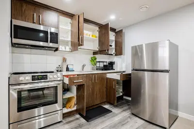 a kitchen with stainless steel appliances and wooden cabinets at Modern 1BR Suite Sleeps 3-4 in Near YYC Calgary Airport in Calgary