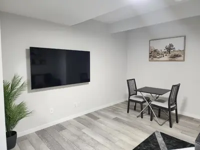 a dining room with a table and a television on a wall at Stylish furnished 2bedroom suite near YYC Airport in Calgary