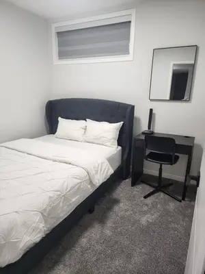 a bedroom with a bed and a desk with a mirror at Stylish furnished 2bedroom suite near YYC Airport in Calgary