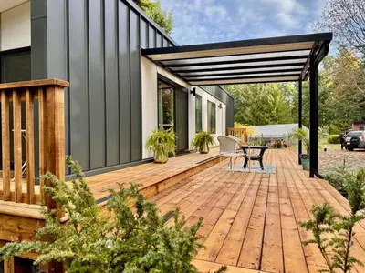 a wooden deck with a table on a house at Island Coastal Retreat in Qualicum Beach