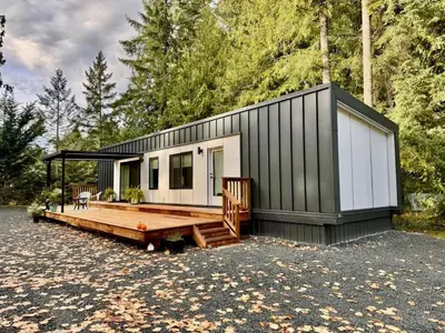 a black and white tiny house with a wooden deck at Island Coastal Retreat in Qualicum Beach