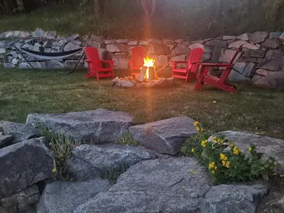 two red chairs sitting around a fire in a yard at NEW Midtown Rossland Studio Apartment in Rossland