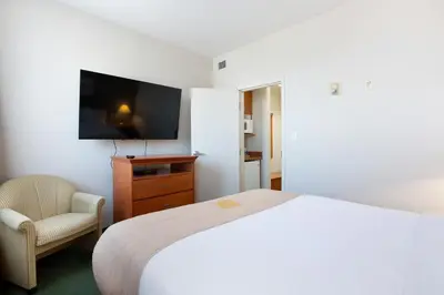 a bedroom with a bed and a chair and a television at Lakeview Inns & Suites - Okotoks in Okotoks