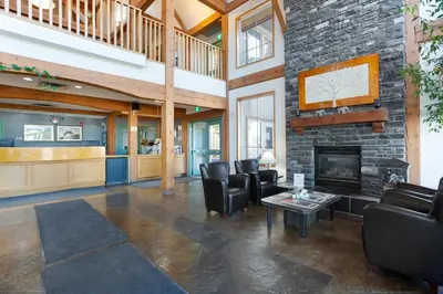 a lobby with leather chairs and a fireplace at Lakeview Inns & Suites - Okotoks in Okotoks