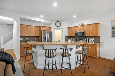 a kitchen with wooden cabinets and a counter with bar stools at The Copperleaf Luxury Retreat with Hot tub in Calgary