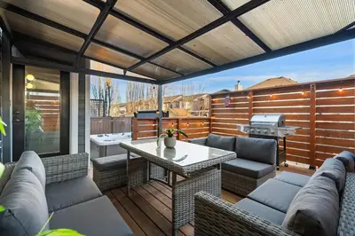 a patio with a table and chairs and a grill at The Copperleaf Luxury Retreat with Hot tub in Calgary