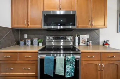 a kitchen with a stove and a microwave at The Copperleaf Luxury Retreat with Hot tub in Calgary