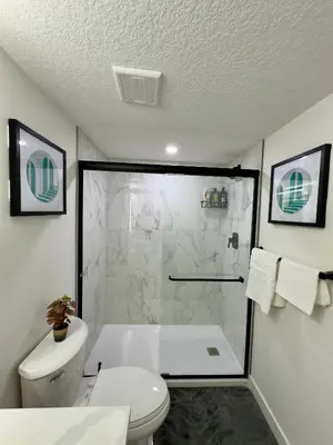 a white bathroom with a shower and a toilet at Sleek Guest Retreat SW EDM BSMT Suite in Edmonton