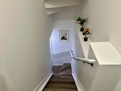 a hallway with white walls and stairs with flowers at Sleek Guest Retreat SW EDM BSMT Suite in Edmonton