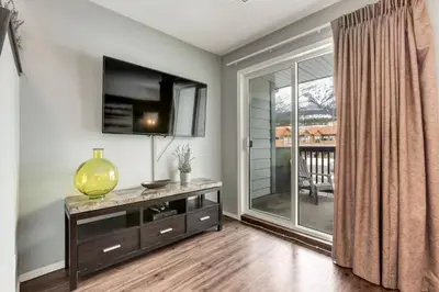 a living room with a entertainment center with a tv and a window at Stunning 3BR Escape with Mountain Views in Canmore in Canmore