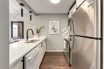 a kitchen with a stainless steel refrigerator and wooden floors at Stunning 3BR Escape with Mountain Views in Canmore in Canmore