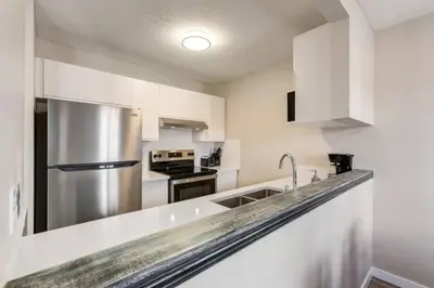 a kitchen with white cabinets and a stainless steel refrigerator at Stylish 3BR Condo in DT Canmore in Canmore