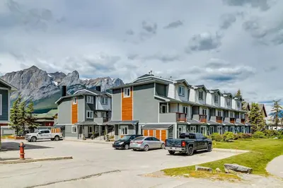 a group of houses with cars parked in a parking lot at Stylish 3BR Condo in DT Canmore in Canmore