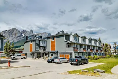 a group of houses and cars parked in a parking lot at Great Rocky Mountain 3BR Condo in Canmore DT in Canmore