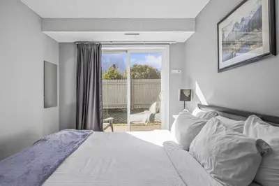 a white bedroom with a bed and a window at Spacious 2BR unit near DT Canmore and Banff in Canmore