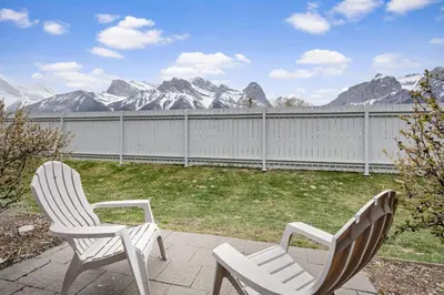 two chairs on a patio with a fence and mountains at Spacious 2BR unit near DT Canmore and Banff in Canmore