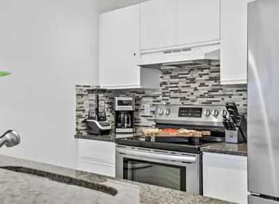 a kitchen with white cabinets and a stove top oven at Rockies 3BR Townhome w Stunning Views Near DT in Canmore
