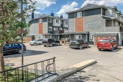 a parking lot with cars parked in front of a building at Rockies 3BR Townhome w Stunning Views Near DT in Canmore