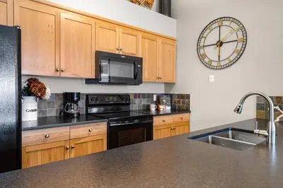 a kitchen with wooden cabinets and a clock on the wall at 3BR Luxury Top Floor Condo with Great views in Canmore