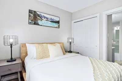 a white bedroom with a bed and two lamps at Newly Renovated 3BR Condo with Hot Tub and MTN Views in Canmore