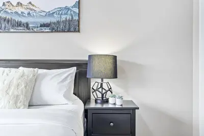 a bedroom with a bed and a lamp on a nightstand at Newly Renovated 3BR Condo with Hot Tub and MTN Views in Canmore
