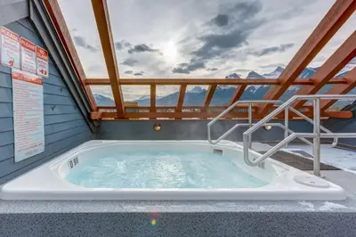 a jacuzzi tub on a balcony with mountains at Spacious 3 BR Condo with Gym and Hot tub in Canmore