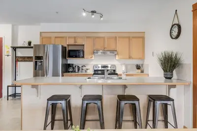 a kitchen with a large counter with stools around it at Spacious 3 BR Condo with Gym and Hot tub in Canmore