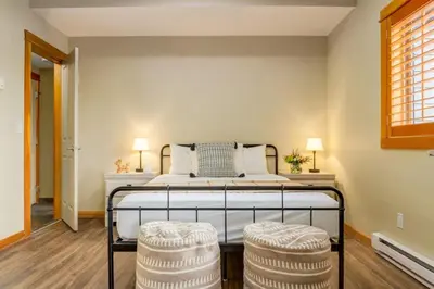 a bedroom with a bed with two stools at Spectacular 3BR Mountain Views with Hot Tub and Gym in Canmore