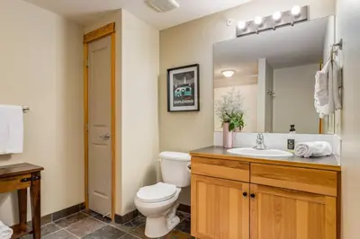 a bathroom with a toilet and a sink and a mirror at Spectacular 3BR Mountain Views with Hot Tub and Gym in Canmore