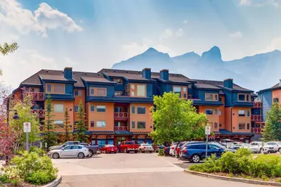 a large building with cars parked in a parking lot at Spectacular 3BR Mountain Views with Hot Tub and Gym in Canmore