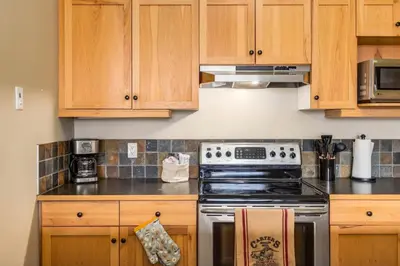 a kitchen with wooden cabinets and a stove top oven at Spectacular 3BR Mountain Views with Hot Tub and Gym in Canmore