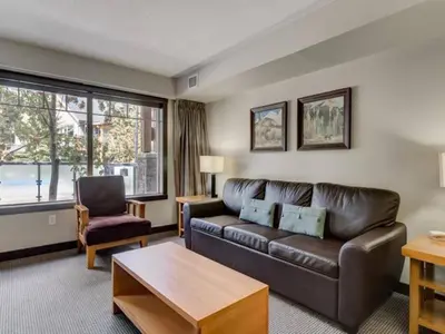 a living room with a leather couch and a table at Comfy 2BR Minutes from Downtown with Hot Tub in Dead Man's Flats