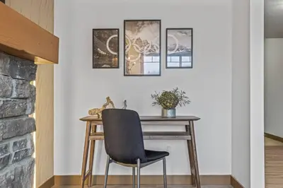 a desk with a chair next to a wall with pictures at Free Arcade Delightful Stay in Rocky Mountains in Dead Man's Flats