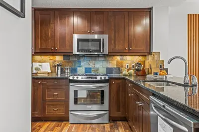 a kitchen with wooden cabinets and stainless steel appliances at 2BR Modern Luxe Condo with Hot Tub and Views in Canmore